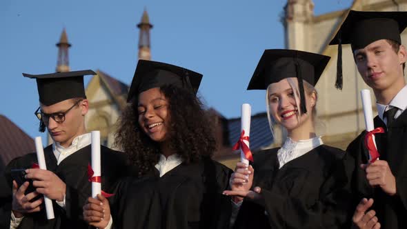 Graduating Students Posing To Camera Showing Their Diplomas. alt