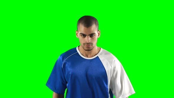 Confident football player standing against green screen alt