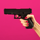 Unrecognizable young woman holding handgun in hand against pink backdrop - PhotoDune Item for Sale