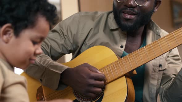 African American father and son playing guitars and singing