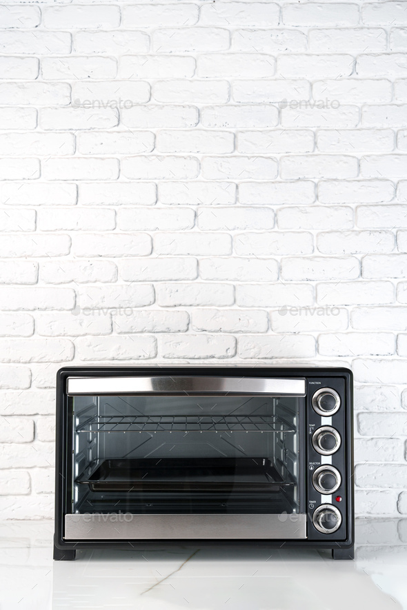 Mini electric oven against white brick wall in the kitchen