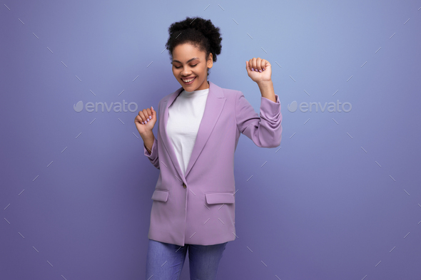 young well-groomed latin secretary woman with fluffy hair is dressed in a lilac jacket on a studio
