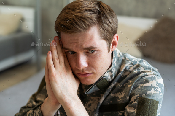 Stressed veteran soldier engrossed in depressive thoughts and memories. Sad depressed young military