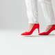 Woman in red high heels and white pants is going, side view, leg in air before step. White back - PhotoDune Item for Sale