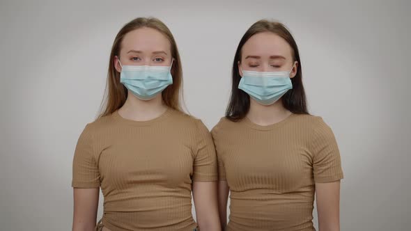 Identical Twins Posing in Covid19 Face Masks at Grey Background alt