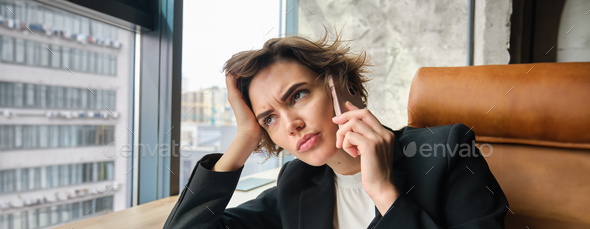 Close up portrait of working woman in an office, having difficult conversation, frowning while