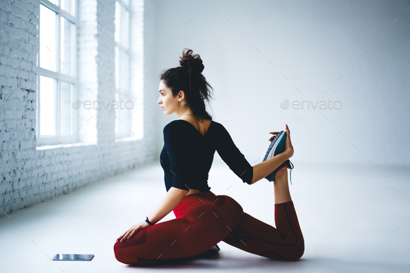 Caucasian female trainer with perfect butt stretching legs during gym  workout for keeping slim figur Stock Photo by GaudiLab