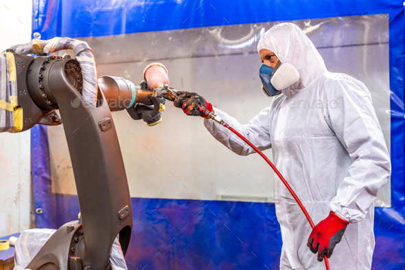 Industrial painter using spray gun to paint a robotic arm