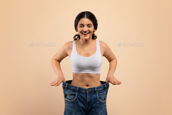 Weight Loss Result. Happy Young Indian Woman Posing In Oversized Jeans