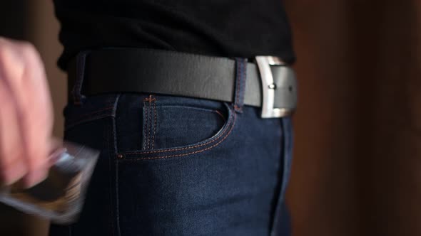 The girl takes the condom out of her jeans pocket, then puts it out and takes it out again. alt