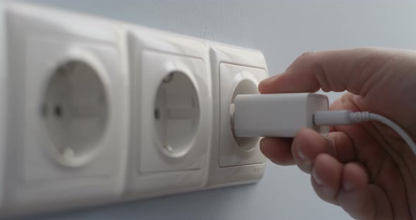 Hand Connecting Electric Plug Usb Charger Into A Wall Socket Concept Of Saving Energy alt