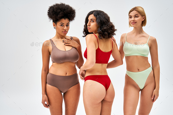 Smiling blonde woman in modern lingerie standing next to multicultural  friends in bras and panties Stock Photo by LightFieldStudios