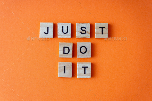 Just do it word. The phrase is laid out in wooden letters top view. Motivation. Orange flat lay