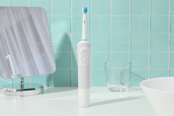 Electric toothbrush, glass and mirror on blue background