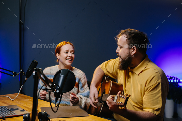 A cheerful couple of radio presenters perform a song on air.