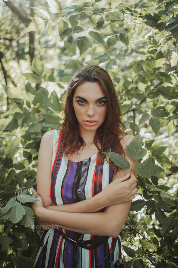 Portrait of an attractive brunette female with striped dress holding ...