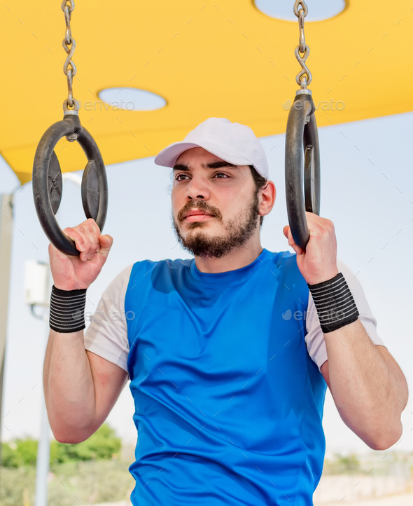 Strong man's hand squeezes the sports gymnastic ring Stock Photo by