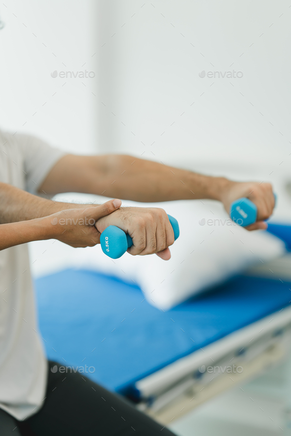 Physical therapist giving exercise by maintaining dumbbells on the arms