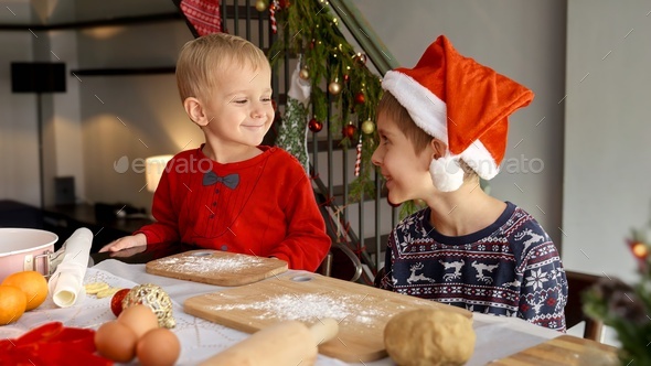 Portrait of little toddler boy smiling at his elder brother sitting table and cooking for Christmas