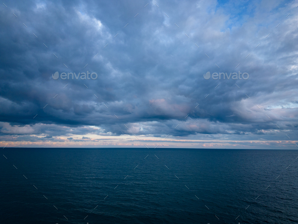 A bird\'s-eye view of a dark sea, horizon, and dramatic sky before a storm in the evening