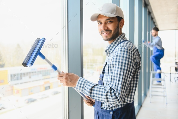 Indian Male professional cleaning service worker cleans the windows and shop windows
