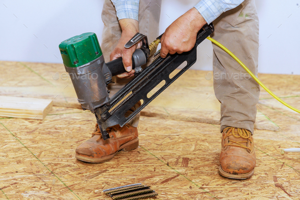 Using an air nail gun to install wooden plywood on floor of a new house