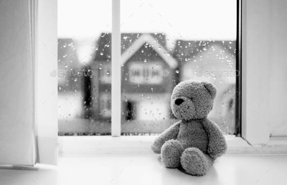 Black and White Sad teddy bear doll sitting next to window in rainy day, Loneliness