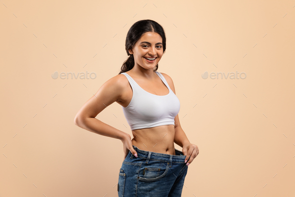 Happy Young Indian Woman Wearing Oversized Jeans Demonstrating Weight Loss Result