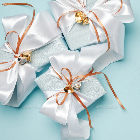 Gift boxes wrapped in blue and silver paper with white and gold ribbon bows.  Stock Photo by TaniaJoy