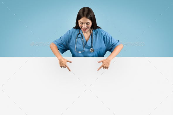 Nurse in blue coat points down at placard