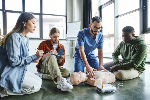 cardiac resuscitation skills, healthcare worker applying defibrillator pads on CPR manikin near