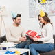 couple celebrating birthday and man presenting birthday gift box to woman in living room - PhotoDune Item for Sale