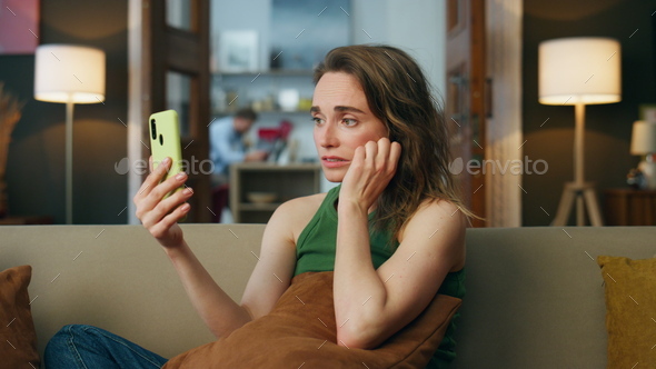 Sad lady talking smartphone home sofa. Depressed woman complaining video chat