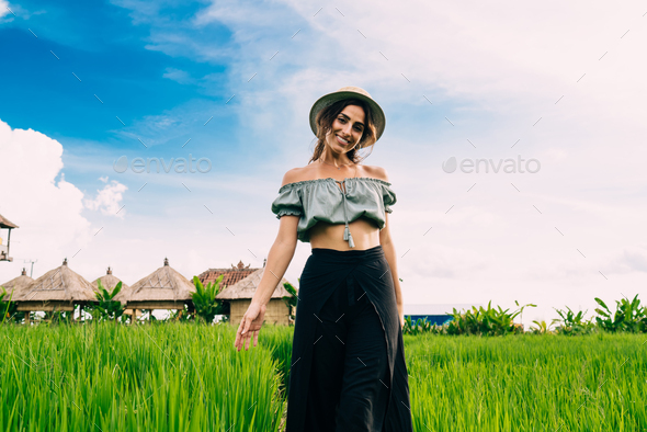 Happy young woman in long skirt standing in field