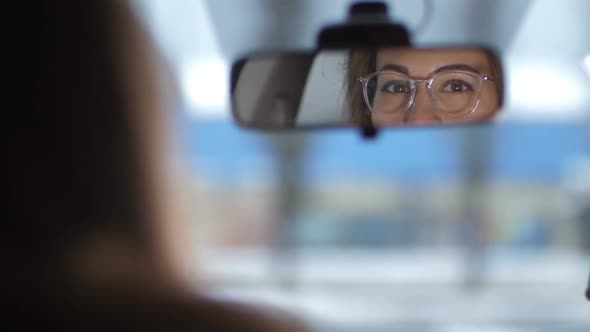 Reflection of Female Eyes in the Front Mirror of the Car alt
