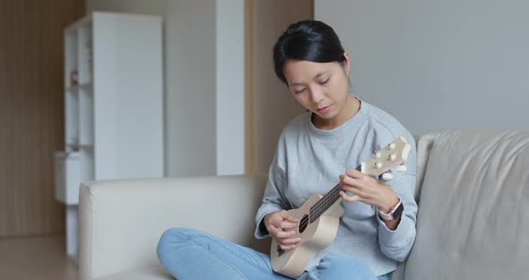 Woman play with ukulele at home