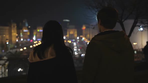 Couple of Teenagers Looking at Night City Lights, Preparing to Run Away Together alt