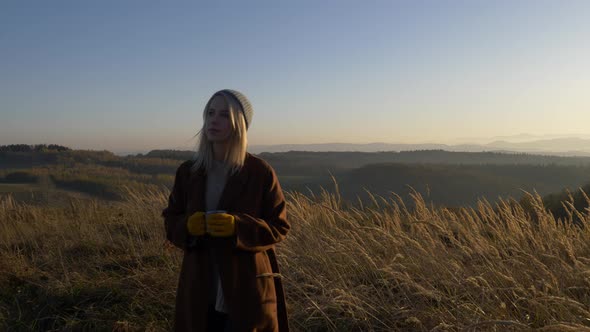 woman hold mug of tea in mountains Sudetes in November in sunset alt