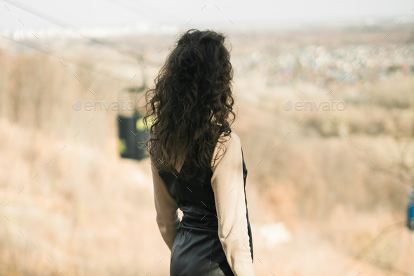 Back view Girl in fall park against background of cable car. Woman