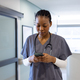 African american female doctor using smartphone in hospital corridor - PhotoDune Item for Sale