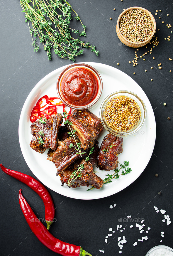 Baked ribs. Roasted pork ribs with spices and herbs on a dark background. Food background