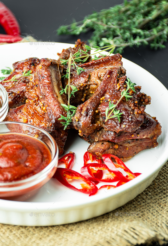 Baked ribs. Roasted pork ribs with spices and herbs on a dark background. Food background