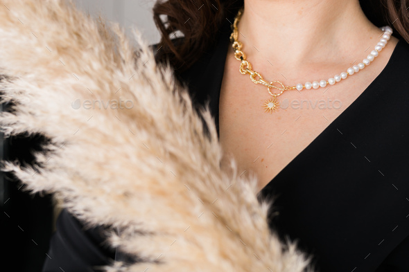 Close-up female in modern pearl and gold necklace chain with pendant. Handmade jewellery and