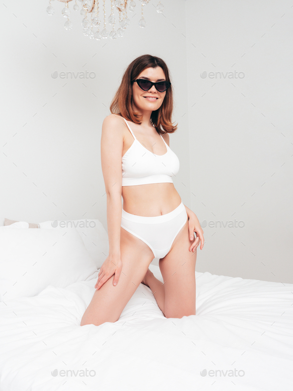 A woman laying on a bed wearing a white underwear photo