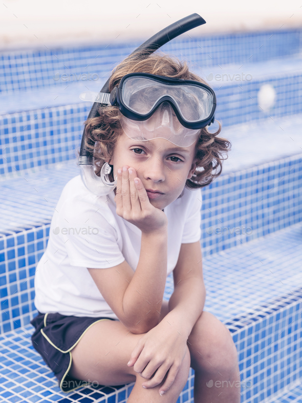 Adorable preteen boy in snorkeling mask sitting on tiled poolsid Stock ...