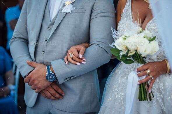 Closeup of bride and groom standing with linked arms during a wedding