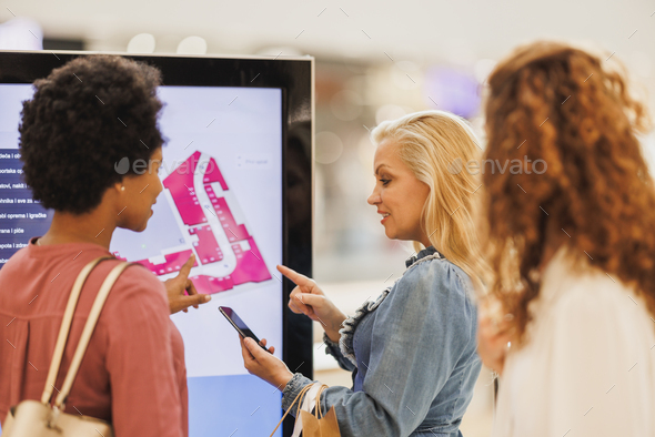 Female Friends Looking For A Store On A Map In The Mall