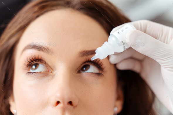 Close up of doctor putting drops into young woman eyes