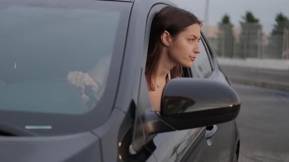 Woman Car Driver Checking Situation on the Road By Leaning Out of the Window alt