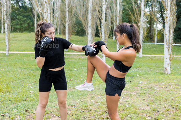 Female boxers training boxing sparring and kicking outdoors